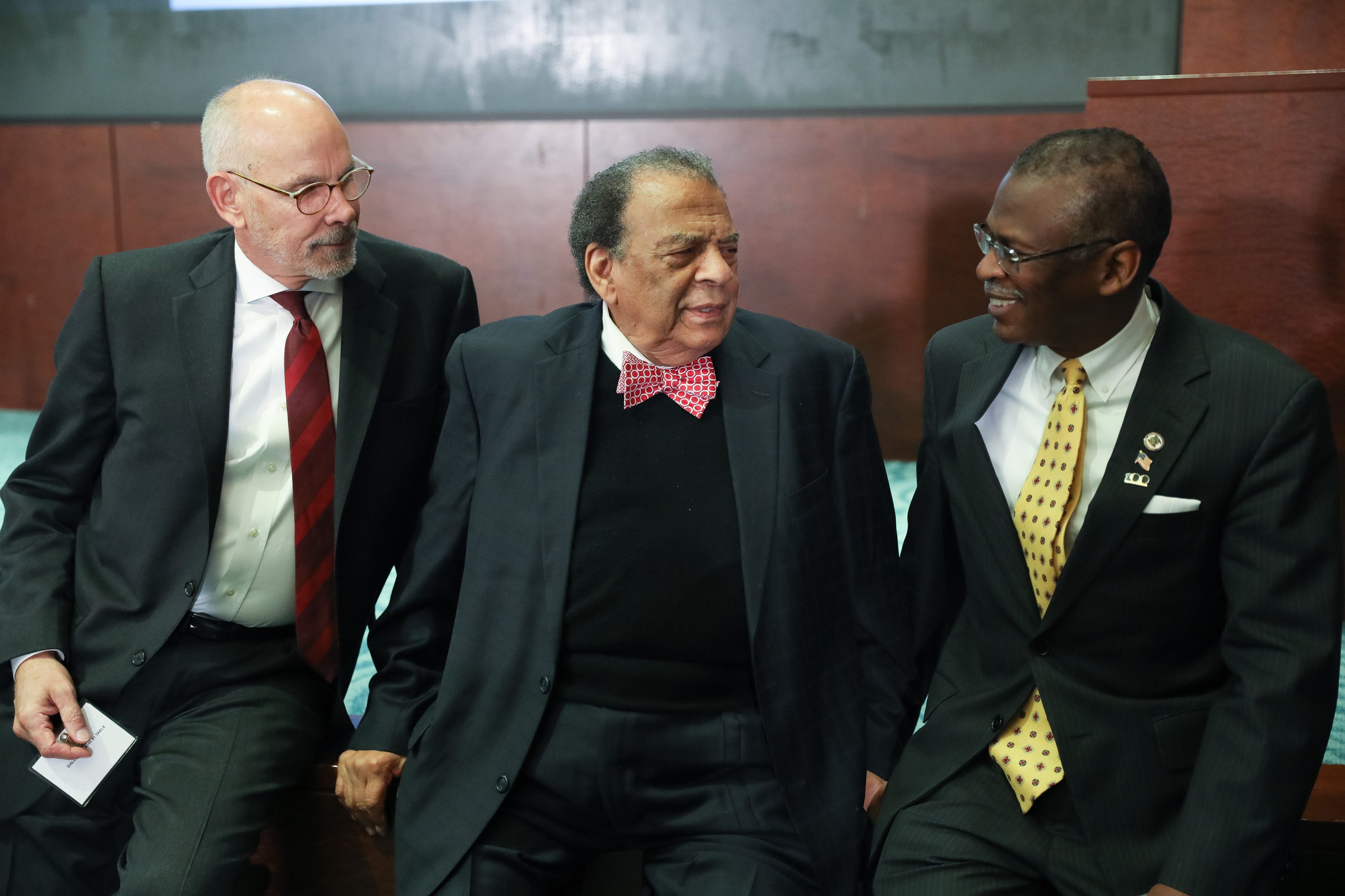 Three suited men seated and talking